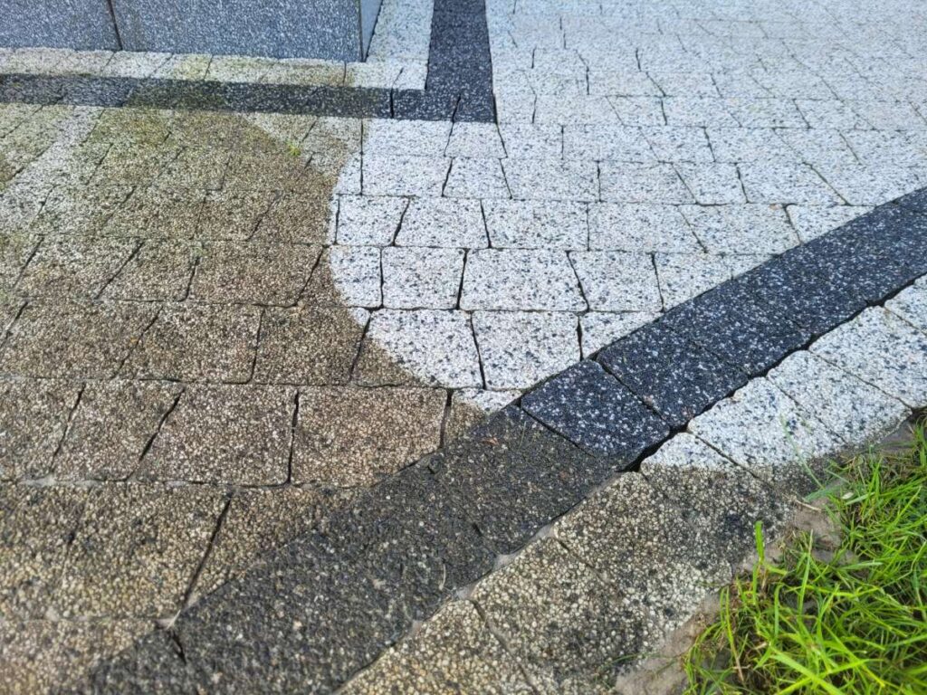 Kontrast przed i po myciu kostki brukowej w Gnieźnie – połowa powierzchni wyczyszczona, połowa z zielonym nalotem.